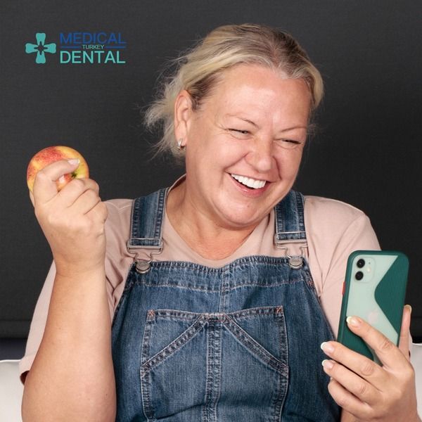 Women smiles with phone after having zirconia crown