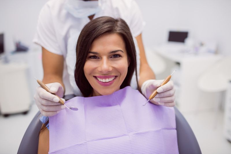 patient sitting in a dental clinic and smiles and a dentist standing behind her